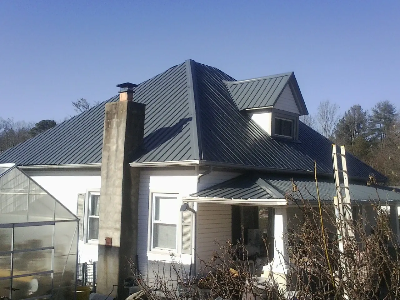Dark blue standing seam metal roof on a white farmhouse with dormer — Slate & Tile Roof Repair by Roofing Brothers in Newberg