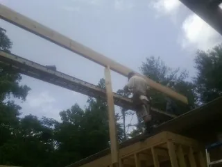Carpenter setting a ridge beam over a new addition frame — Ice Dam Removal by Roofing Brothers in Newberg