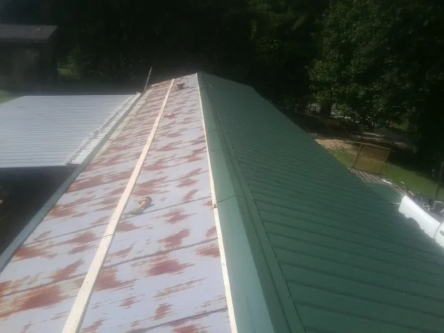 Old rusted panels beside newly installed green metal roofing — Wind Damage Roof Repair by Roofing Brothers in Newberg
