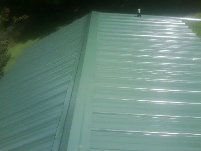 New green metal panels meeting at the ridge of a roof — Flat Roof Repair work by our crew in Newberg