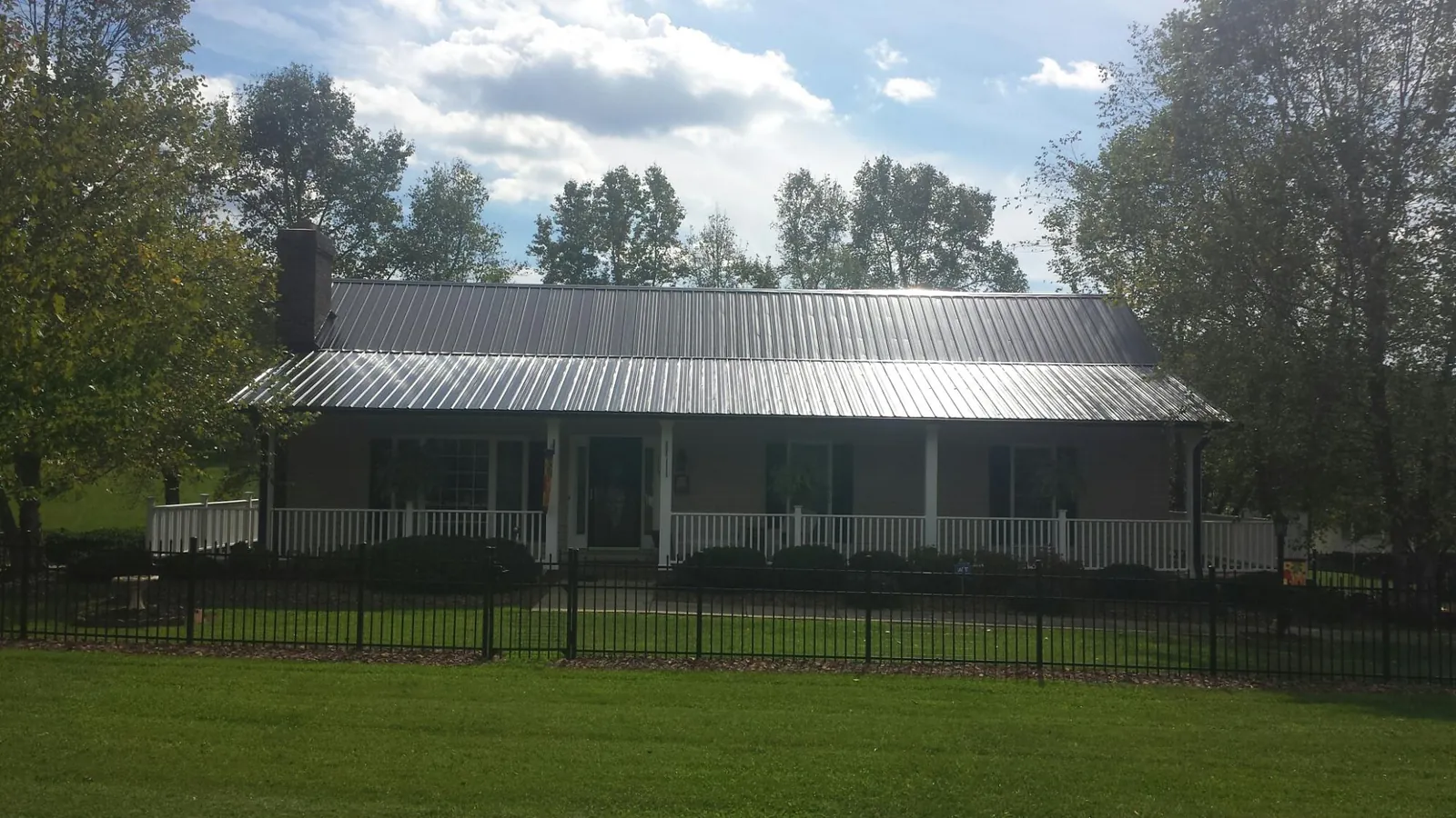Gray metal roof on a brick ranch with a full width front porch — Gutter Guard Installation work by our crew in Newberg