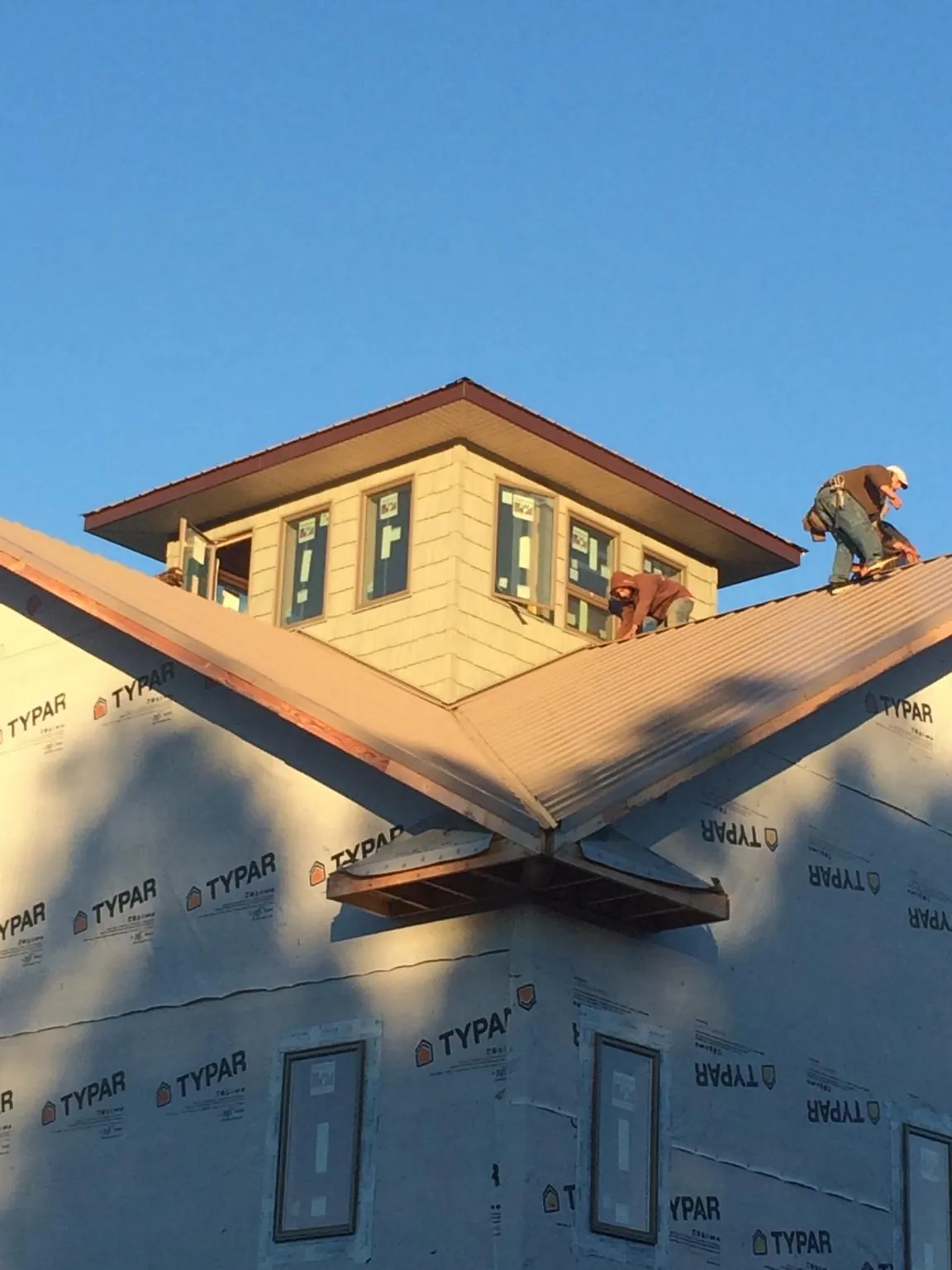Roofers working around a rooftop cupola on a new metal roof at sunset — Roof Waterproofing in Newberg by Roofing Brothers
